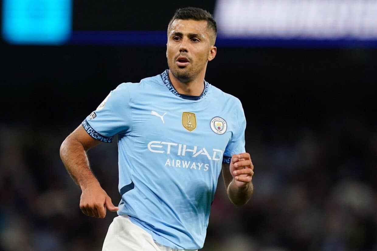 Rodri in maglia Manchester City durante una partita ufficiale, concentrato nel suo ruolo da centrocampista centrale.