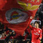 João Félix con la maglia del Benfica festeggia sotto una grande bandiera del club allo stadio