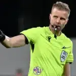 Arbitro UEFA indica una direzione durante una partita
